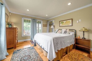 A bedroom with a bed, a nightstand, a lamp, a dresser, and a window with curtains. - Orchard Park cottage (Versailles)