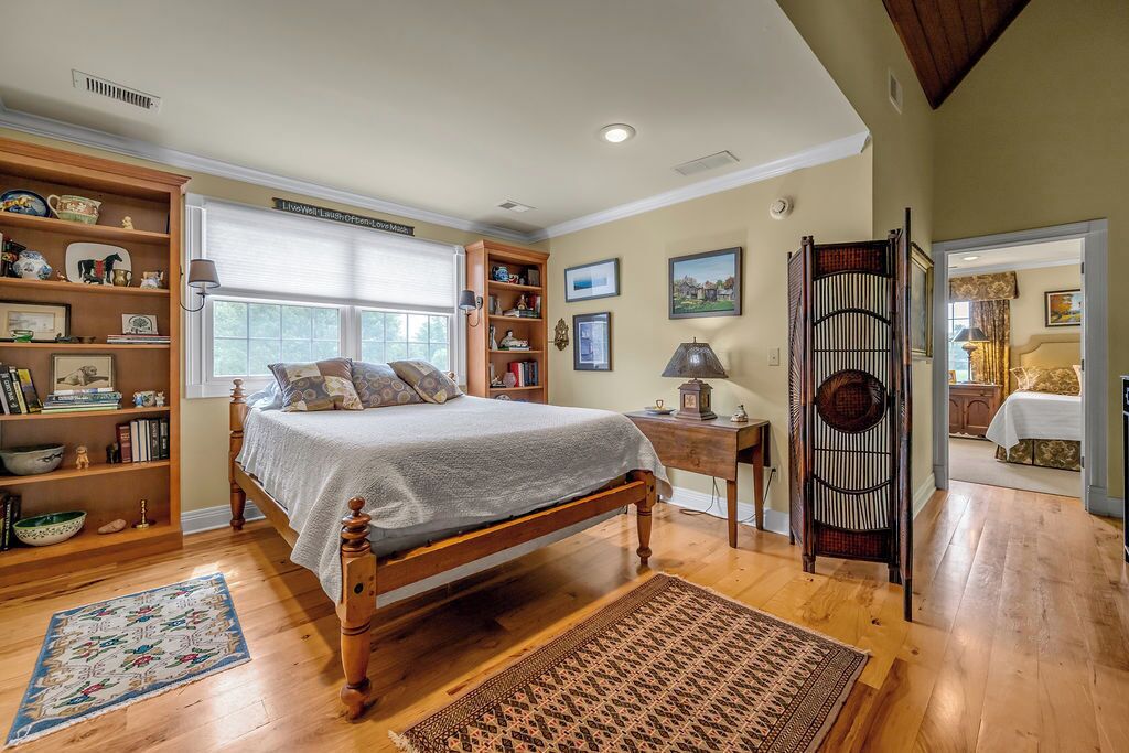 A bedroom with a wooden bed, a bookshelf, a desk, and a chair.