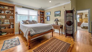 A bedroom with a wooden bed, a bookshelf, a desk, and a chair. - Orchard Park cottage (Versailles)