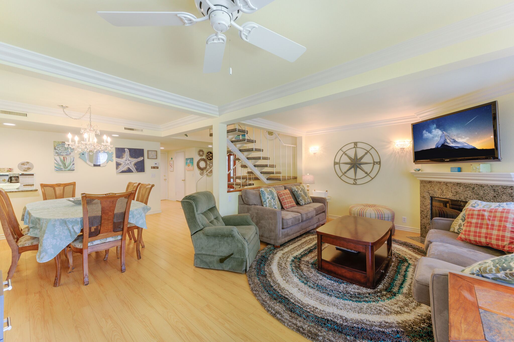 A spacious living room with a dining area, a staircase, and a fireplace.