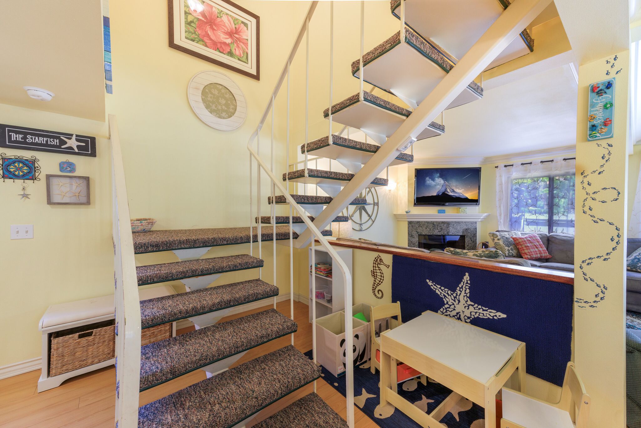 Ein mehrstöckiger Innenraum mit Treppe, Essbereich und Fernseher.