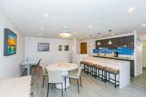 Une cuisine moderne dotée d’un îlot central, de tabourets de bar et d’un coin repas avec une table ronde et des chaises.