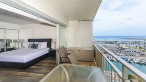 A balcony with a bed, a chair, and a table. - Great Ocean View At The Ilikai Hotel! (Honolulu)