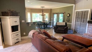 A living room with a brown leather sofa, a white cabinet, a dining area with a table and chairs, and a fireplace. - "Lake Lanier Islands House Rental"  (Buford)