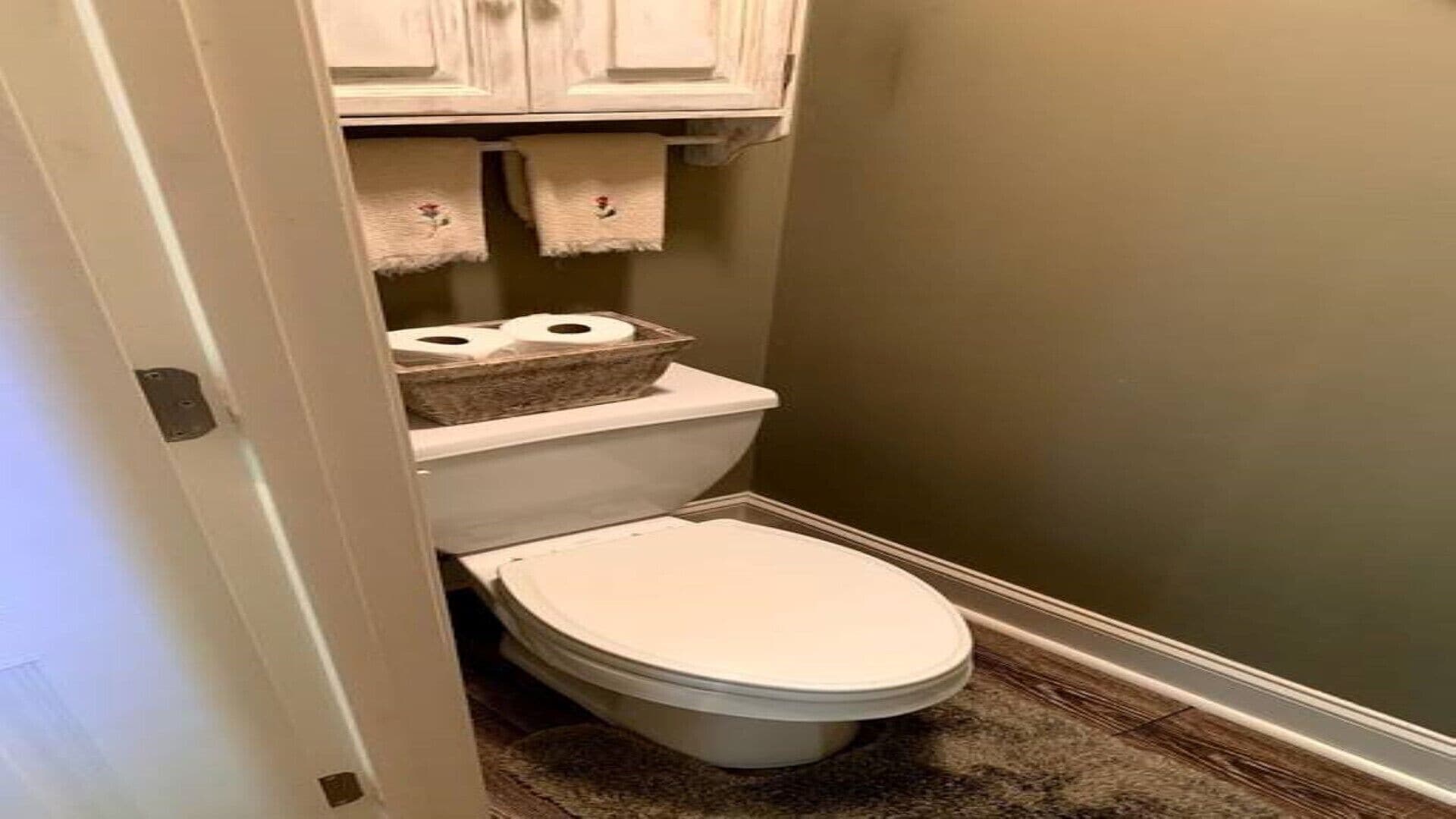 Un baño pequeño con un inodoro, un cubo de basura y un armario sobre el inodoro.