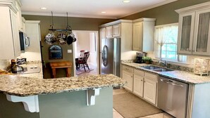 A kitchen with granite countertops, stainless steel appliances, and light-colored cabinetry. - "Lake Lanier Islands House Rental"  (Buford)