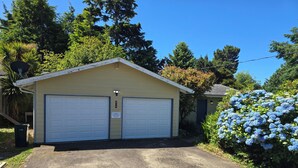 A two-car garage with a beige exterior, a small attached shed, and a well-maintained driveway. - Cute Rockaway Beach Cabin (Rockaway Beach)