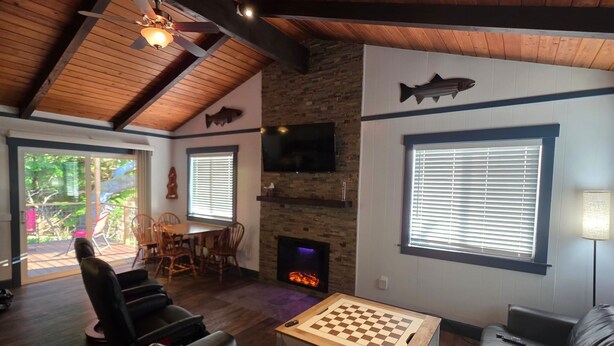 A cozy living room with a fireplace, a mounted fish decoration, a chess table, and comfortable seating. - Cute Rockaway Beach Cabin (Rockaway Beach)