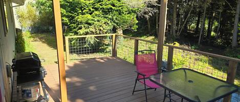 Eine Holzterrasse mit Grill, Tisch und Stuhl.