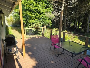A wooden deck with a grill, a table, and a chair. - Cute Rockaway Beach Cabin (Rockaway Beach)