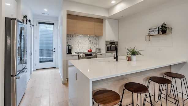 Una cocina moderna con una isla grande, taburetes de bar y un cartel de bienvenida.