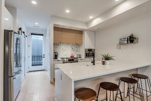 A modern kitchen with a large island, bar stools, and a welcome sign. - Downtown Central 9th SLC Loft Walk or Trax to Convention Center (Salt Lake City)