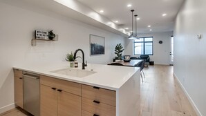Una cocina moderna con una isla grande, armarios blancos y un lavavajillas integrado.