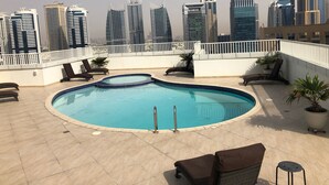Ein Pool auf dem Dach mit Liegestühlen und Blick auf hohe Gebäude.