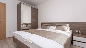Un dormitorio moderno con una cama grande, un armario y una mesita de noche.