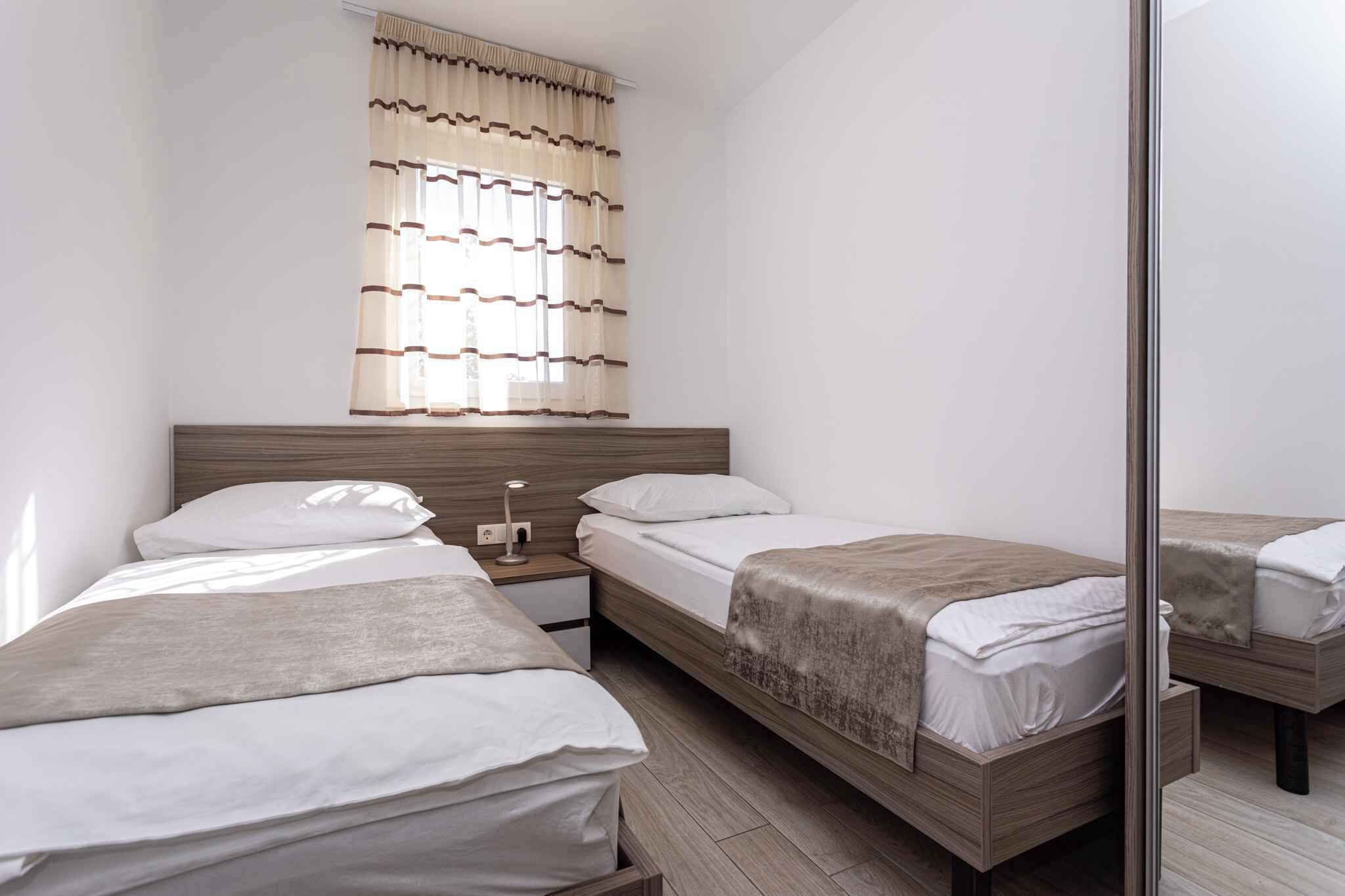 Habitación de hotel con dos camas, una mesita de noche, un espejo y un ventanal con cortinas a rayas.