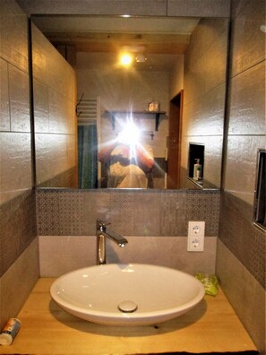 Ein Badezimmer mit Waschbecken, Spiegel und einer Handseife an der Wand.