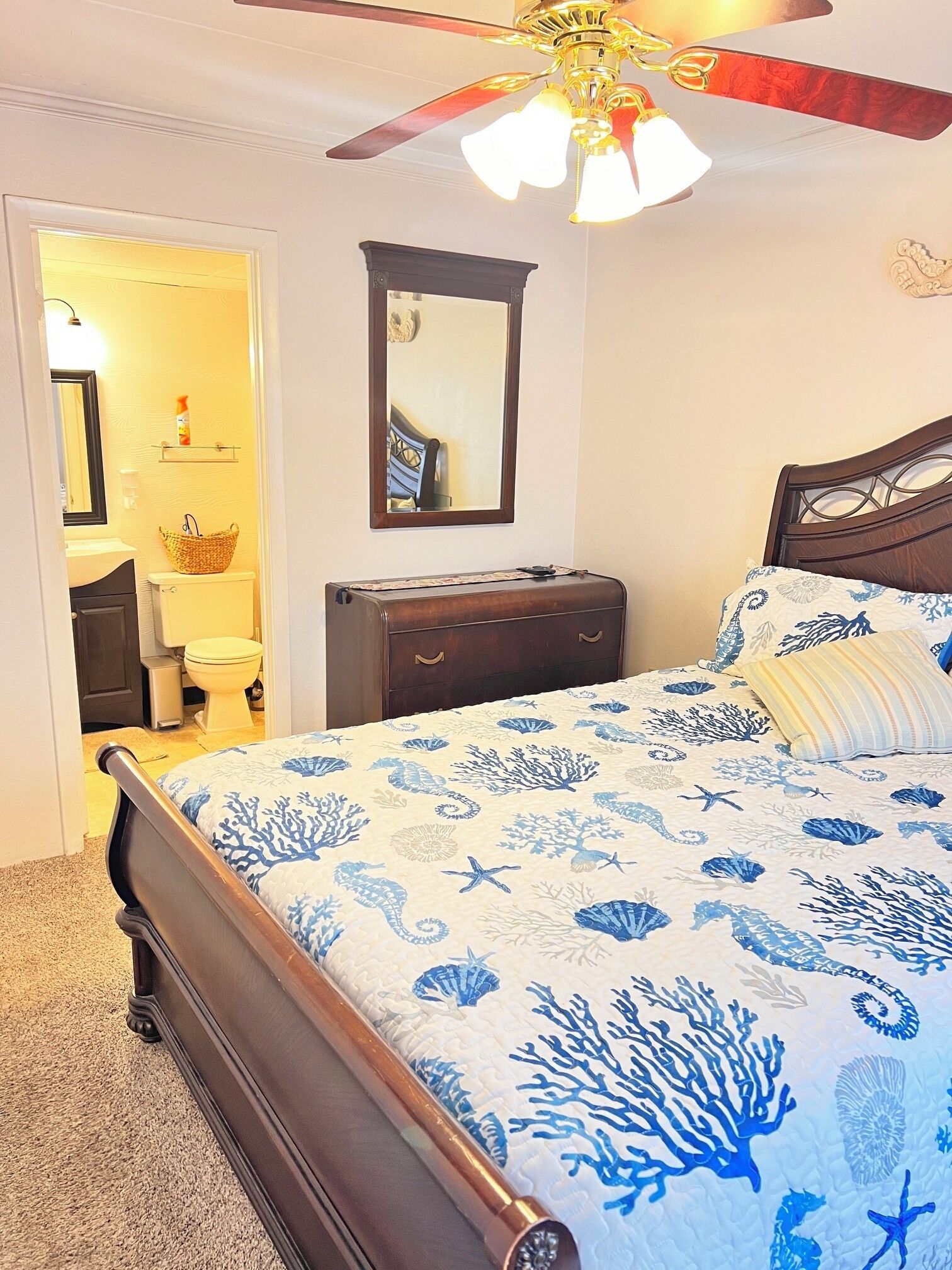 A bedroom with a bed, a dresser, a mirror, and a ceiling fan.
