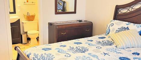 A bedroom with a bed, a dresser, a mirror, and a ceiling fan.
