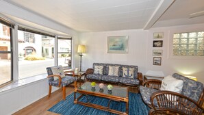 Un salon comprenant un canapé, des fauteuils, une table basse et donnant sur l’extérieur.