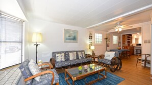 Un salon comprenant un canapé, des fauteuils, une table basse et un coin repas avec une table et des chaises.