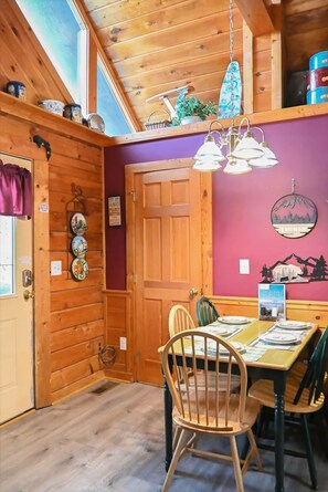 A wooden interior with a dining table, chairs, and a ceiling light fixture. - Adventure Awaits, 1mi to the parkway, dog friendly (Pigeon Forge)