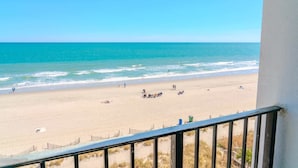 A beach view from a balcony with a railing, sandy beach, ocean, and clear sky. - The Four Oh One | Palace (Myrtle Beach)