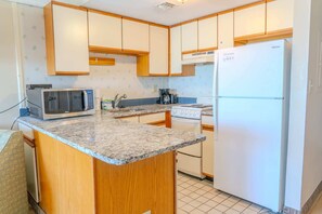 Una cocina con armarios de madera, microondas, estufa y refrigerador.
