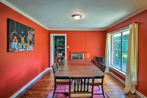 A dining room with a long table and chairs, a fireplace, and a large window with curtains. - Secluded Baton Rouge Area Hideaway w/ Lawn! (Clinton)