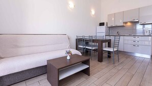 Un espacio habitable moderno y funcional con sofá, mesa de comedor con sillas y kitchenette.