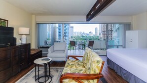Ein Hotelzimmer mit Balkon, Bett, Sofa, Fernseher und Schreibtisch.