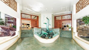 A spacious lobby with a central fountain, a staircase, and a reception area.