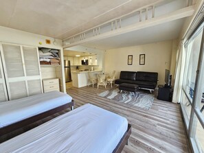 A compact hotel room with a kitchenette, a sofa, a TV, and a bed.