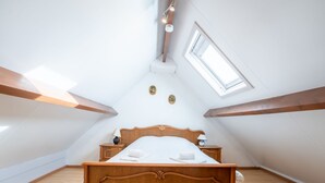 A bedroom with a wooden bed, two bedside tables, a skylight, and a wooden ceiling beam. - Vissershuisje 9/18 with parking by Interhome (Bredene)