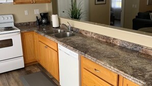 Une cuisine avec des meubles en bois, des plans de travail en granit, une cuisinière blanche et un lave-vaisselle.