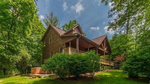 A wooden cabin with a porch, surrounded by lush greenery and trees. - THE MOUNTAIN LAUREL |GORGEOUS MOUNTAIN VIEWS (Hiawassee)