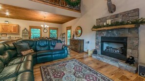 A spacious living room with a fireplace, a leather sofa, and a decorative rug. - THE MOUNTAIN LAUREL |GORGEOUS MOUNTAIN VIEWS (Hiawassee)