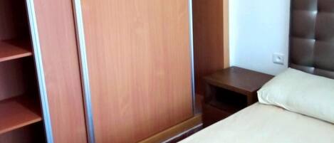 A bedroom with a bed, a nightstand, and a wardrobe.