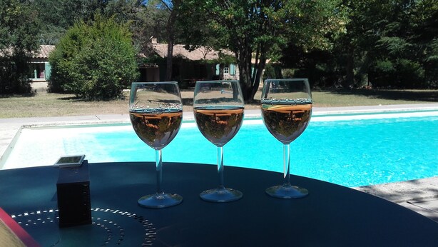Tres copas de vino con una piscina al fondo.