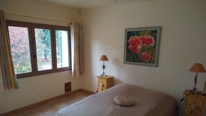 Un dormitorio con una cama grande, dos mesitas de noche con lámparas, un cuadro en la pared y una ventana con cortinas.