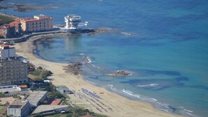 A coastal hotel with a beach, ocean view, and multiple buildings.