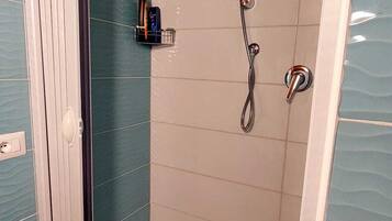 A walk-in shower with a glass door, tiled walls, and a handheld showerhead.