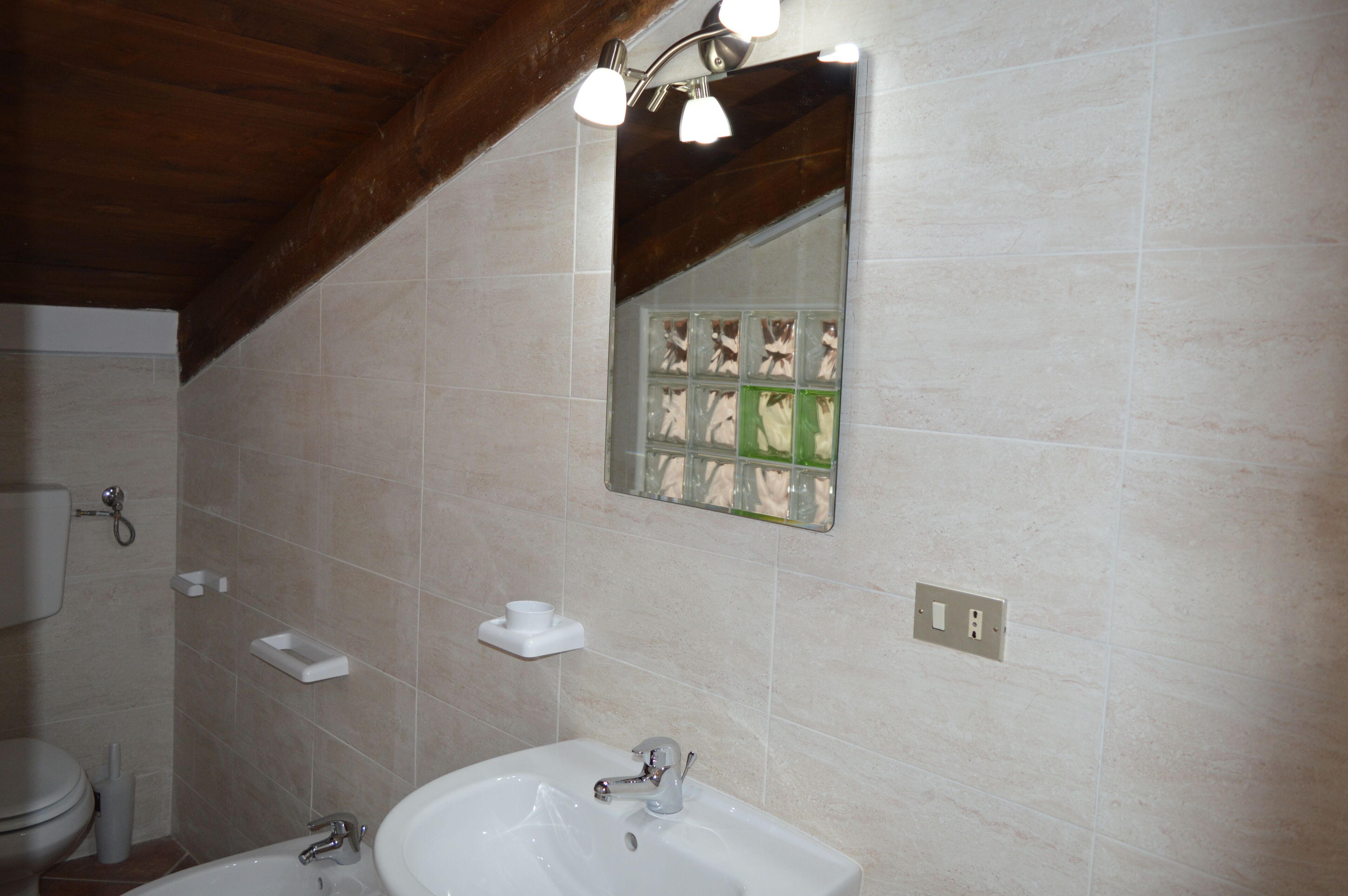 A bathroom with a white sink, a mirror with a decorative frame, and a toilet.