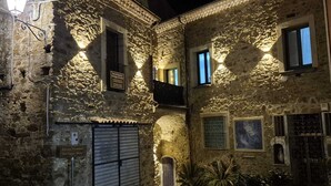 A stone building with a closed metal gate, a small balcony, and potted plants.