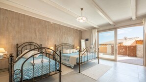 A bedroom with two metal beds, a large window, and a view of the outside. - Luxurious Holiday Home with Pool, Terrace, Wi-Fi & Air Conditioning; Parking Available, Smaller Pets Allowed (domus de maria)