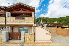 A two-story building with a stone facade, wooden beams, and a gated entrance. - Luxurious Holiday Home with Pool, Terrace, Wi-Fi & Air Conditioning; Parking Available, Smaller Pets Allowed (domus de maria)
