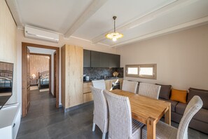 A modern kitchen with dark countertops, a wooden dining table, wicker chairs, and a sofa with cushions. - Luxurious Holiday Home with Pool, Terrace, Wi-Fi & Air Conditioning; Parking Available, Smaller Pets Allowed (domus de maria)