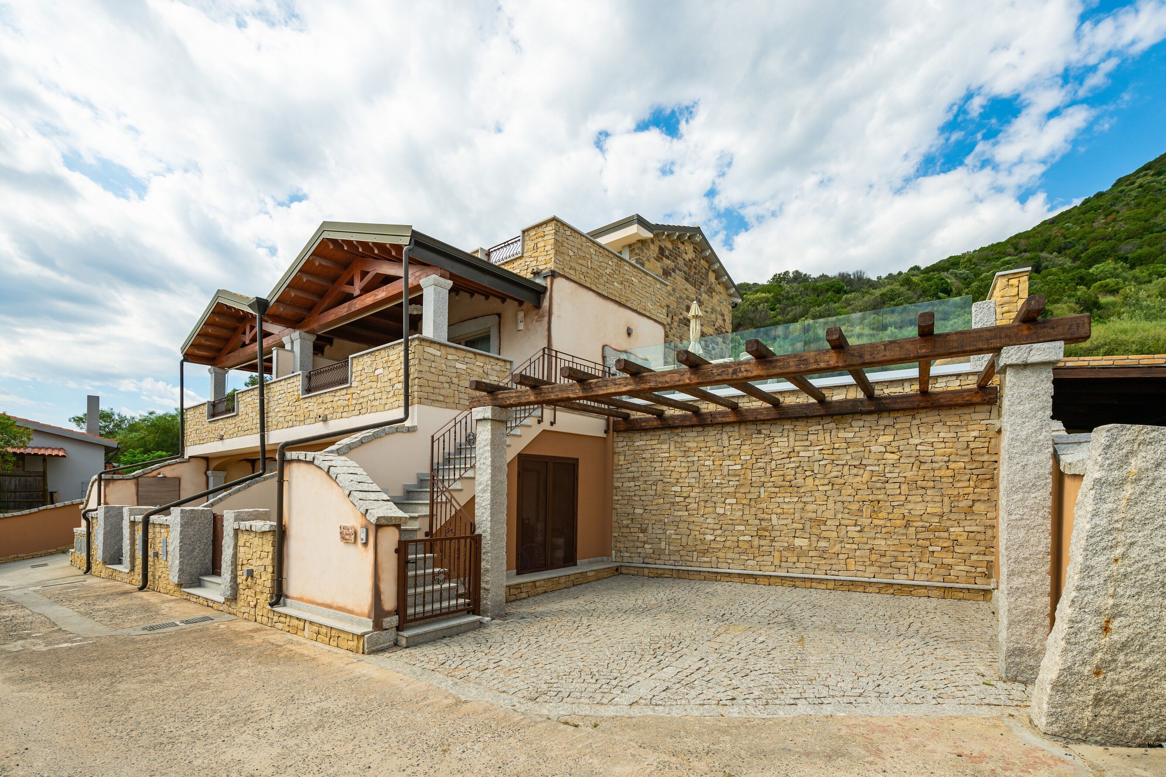 Una casa de dos pisos con fachada de piedra, un balcón de madera y una escalera de piedra que lleva al piso superior.