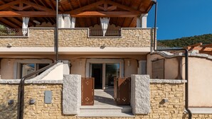 A two-story stone building with a balcony, a wooden roof, and a stone entrance. - Luxurious Holiday Home with Pool, Terrace, Wi-Fi & Air Conditioning; Parking Available, Smaller Pets Allowed (domus de maria)