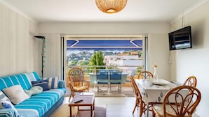 Ein modernes Wohnzimmer mit Sofa, Esstisch, Stühlen und Blick auf eine Stadtansicht.